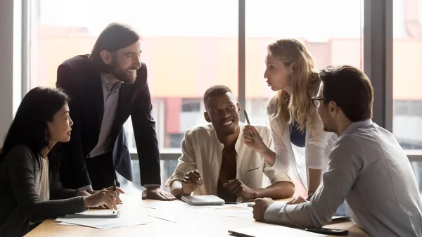 Gelukkige gemengde ras oude en jonge collega 's praten op vergadering. — Stockfoto