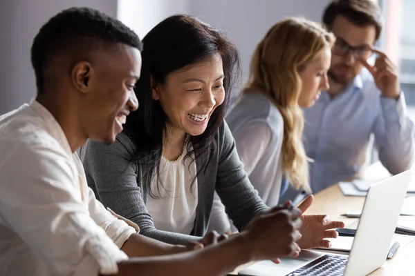 Glad gammal koreansk affärskvinna som jobbar på dator med afrikansk kollega. — Stockfoto