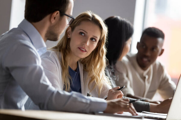 Young female employee discussing project ideas with male leader.