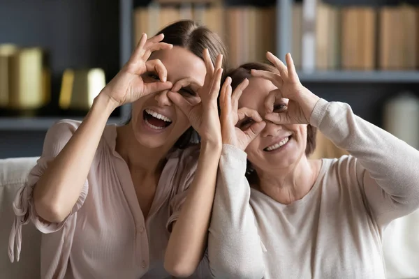 Huvudet sköt vuxen dotter och mogen mor gör kikare gest — Stockfoto