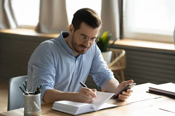 Heureux concentré jeune homme d'affaires trentaine écrivant des notes dans le planificateur de papier. — Photo