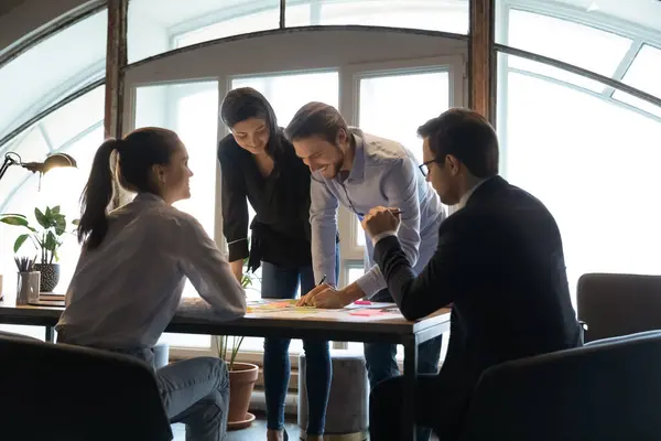 Équipe d'employés divers travaillant sur des documents de projet, écrivant des notes — Photo