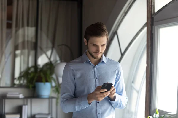 Close-up zelfverzekerde zakenman met behulp van telefoon, stand in office — Stockfoto