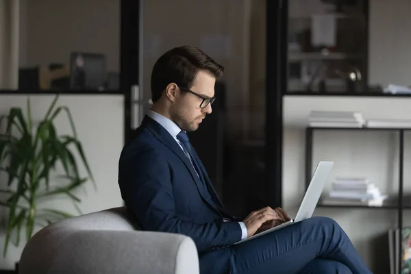 Уверенный в себе бизнесмен в очках, работающий на ноутбуке — стоковое фото