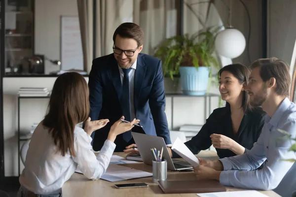 Smiling team leader with employees listening to businesswoman at meeting — Stock Photo, Image