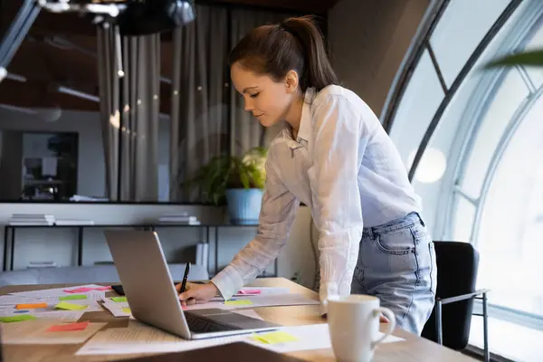 Confident businesswoman writing notes, working with project documents in office