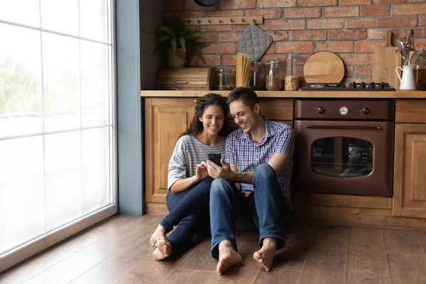 Happy couple relax at home kitchen using cellphone — Stock Photo, Image