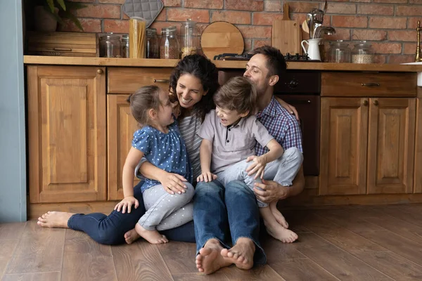 Glückliche Eltern spielen zu Hause mit zwei kleinen Kindern — Stockfoto