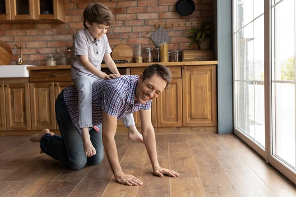 Happy little boy ride young dad playing at home — Stock Photo, Image