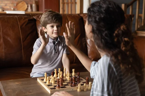 Feliz niño pequeño dar chequeo cinco jugando ajedrez con mamá — Foto de Stock