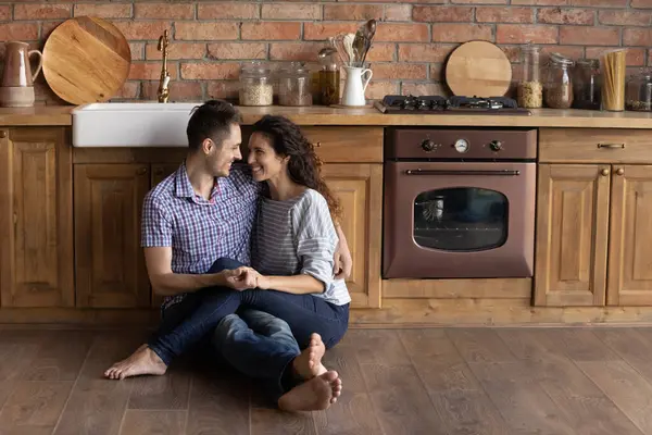 Счастливая пара тысячелетия расслабиться обнимаясь на собственной кухне — стоковое фото