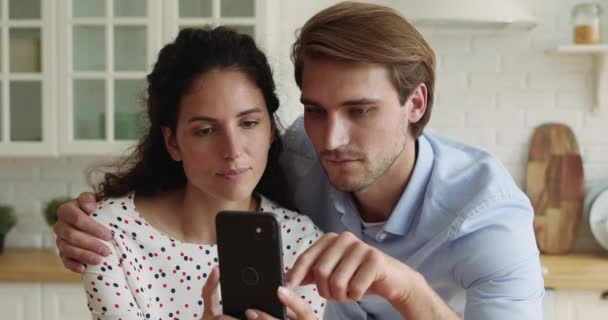 Uczuciowa millenium kaukaska rodzina para patrząc na ekran smartfona. — Wideo stockowe
