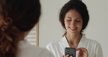 Teknolojiye bağımlı beyaz bornozlu genç bir kadın telefon kullanıyor..