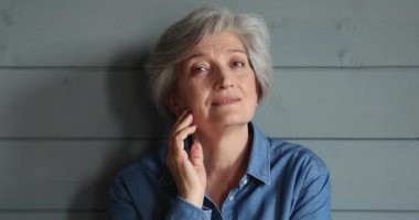 Stüdyoda poz veren yaşlanmış gri saçlı kadın portresi.