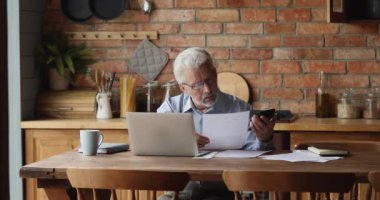 Yaşlı adam aylık giderleri hesaplar, ödeme makbuzlarını kontrol eder