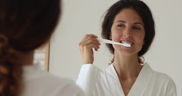 Feliz milenaria hermosa mujer en albornoz cepillarse los dientes. — Vídeo de stock