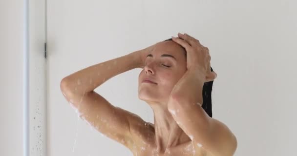 Hermosa mujer milenaria lavando el cabello mientras se ducha. — Vídeo de stock