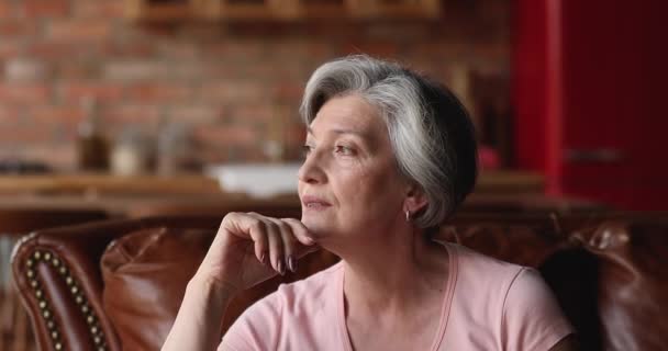 Mulher de meia-idade atraente sentar no sofá olhando para a distância — Vídeo de Stock