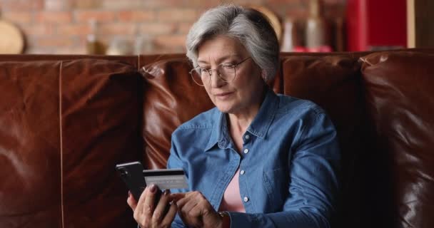 持有信用卡和智能手机上网购物的老年妇女 — 图库视频影像