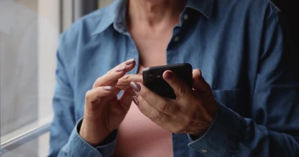 Vista de cerca manos femeninas sosteniendo teléfono inteligente desplazamiento noticias feed — Vídeo de stock