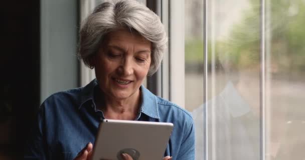 Orta yaşlı kadın ayakta duruyor, tablet kullanıyor. — Stok video