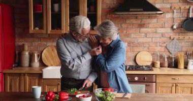 Mutlu yaşlı eşler, mutfakta sebze salatası hazırlıklarının keyfini çıkarıyorlar.