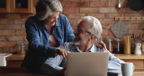 Glückliche ältere Eheleute verbringen Zeit mit Laptop in der Küche — Stockvideo