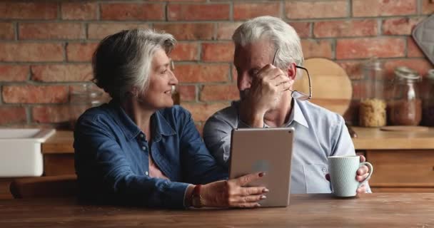 Los cónyuges mayores discuten el pedido de comida a domicilio usando un dispositivo de tableta — Vídeos de Stock