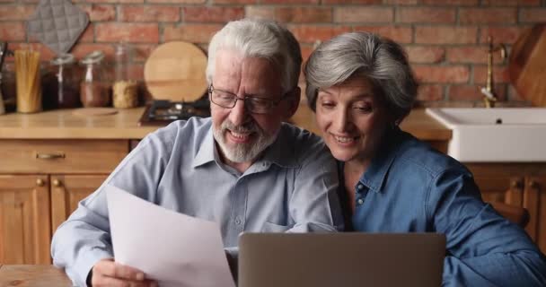 Ouder paar zitten in de keuken lezen overeenkomst voel me blij — Stockvideo