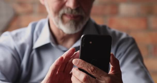 Vue rapprochée homme plus âgé en utilisant smartphone assis à l'intérieur — Video