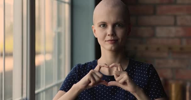 Ung skallig cancer patient kvinna visar med fingrar hjärtform — Stockvideo