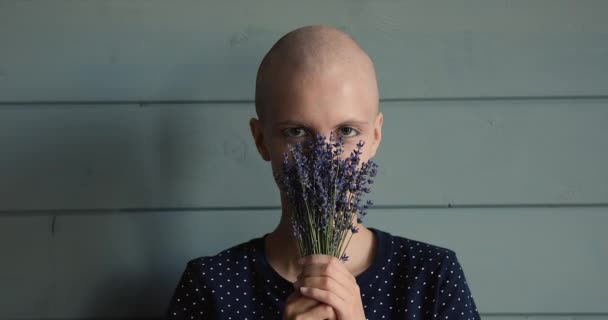 Careca paciente câncer feminino feliz com flores posar em estúdio — Vídeo de Stock