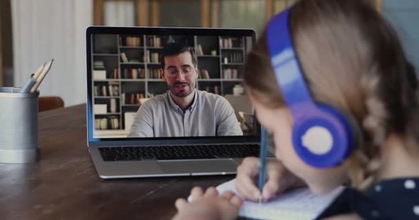 View over kid shoulder sit at table listens online teacher — Stock Video