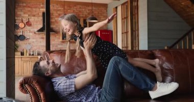 Baba kanepede uzanmış tatlı kızıyla oynuyor.