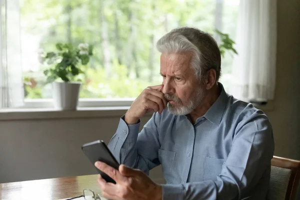 Крупный план стресс недовольный зрелый мужчина смотрит на экран телефона — стоковое фото