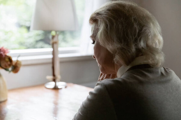 Close up unhappy thoughtful mature woman lost in thoughts