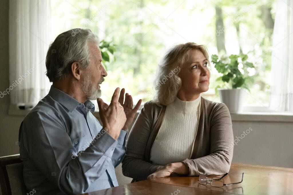 Offended mature woman ignoring husband, elderly couple arguing