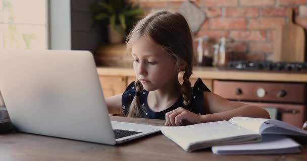 Маленька чарівна дівчинка навчається вдома за допомогою ноутбука — стокове відео