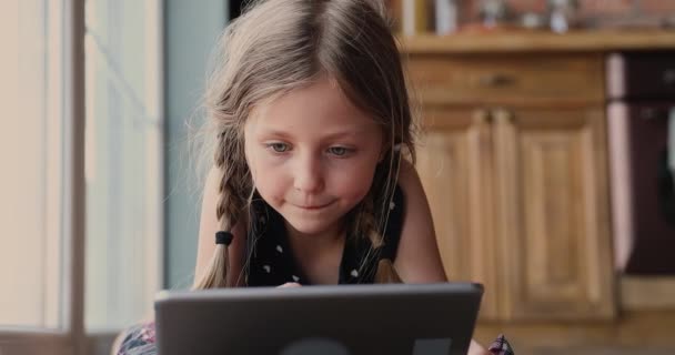 Χαριτωμένο κοριτσάκι με κοτσίδες που βρίσκονται σε εσωτερικούς χώρους με συσκευή tablet — Αρχείο Βίντεο