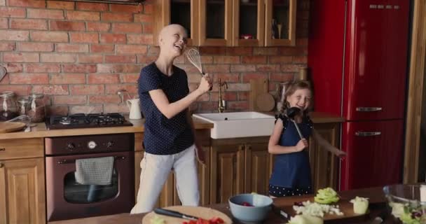 Lilla dotter hennes skalliga mamma cancer patient sjunger i köket — Stockvideo