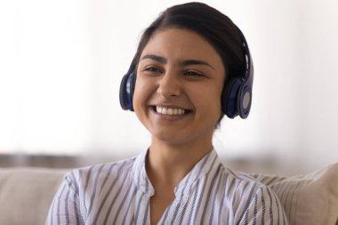 Ses kitabı dinleyen, kulaklıklı, pozitif Hintli genç bayan.