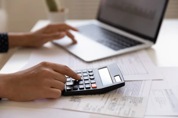 Молодая женщина-клиент электронного банка использует калькулятор в бумажной работе — стоковое фото