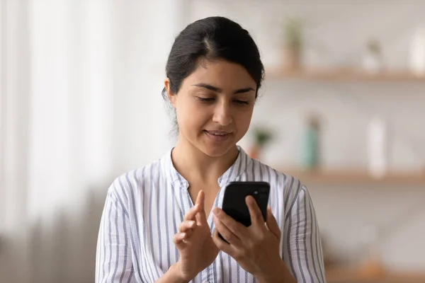 Pleasant millennial mixed race woman use mobile phone at home
