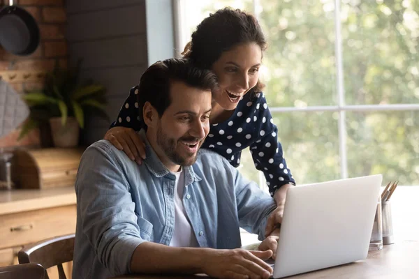 Amazed couple shocked by unexpected news on laptop