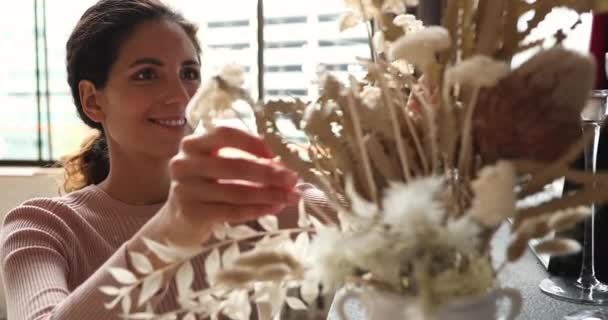 Usmívající se tisíciletá žena styling suché květiny ve váze, zdobení domu. — Stock video