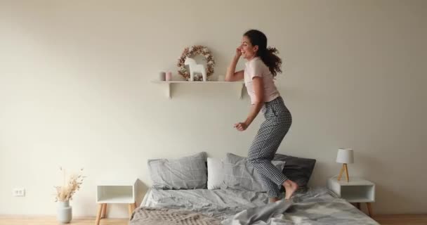 Dolblij duizendjarige vrouw dansen op muziek op bed. — Stockvideo