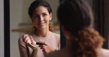 Çekici genç bir kadın yüz pudrası uyguluyor ya da fırçayla kızarıyor..