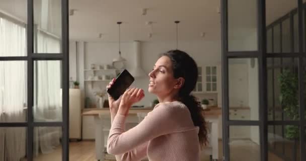 Émotionnel réjoui 30s jeune femme dansant, tenant smartphone dans les mains. — Video