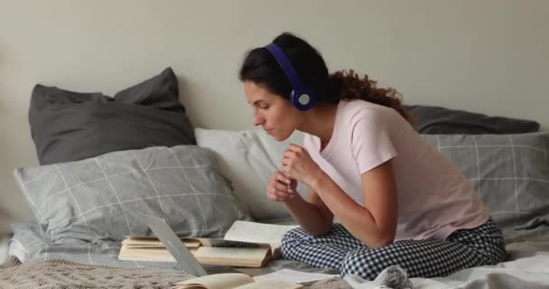 Leende smart vacker kvinna studerar online, sitter på sängen. — Stockvideo