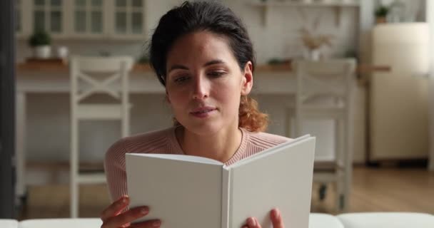 Lächelnde junge schöne Frau liest Papierbuch. — Stockvideo